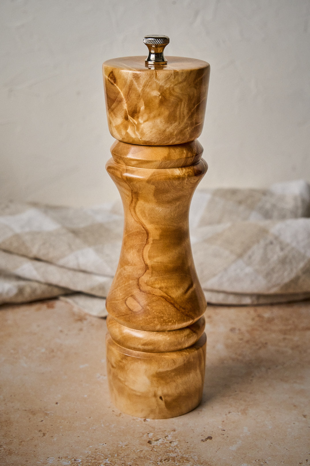 Close-up showing the unique marbling birch wood of the handmade pepper grinder