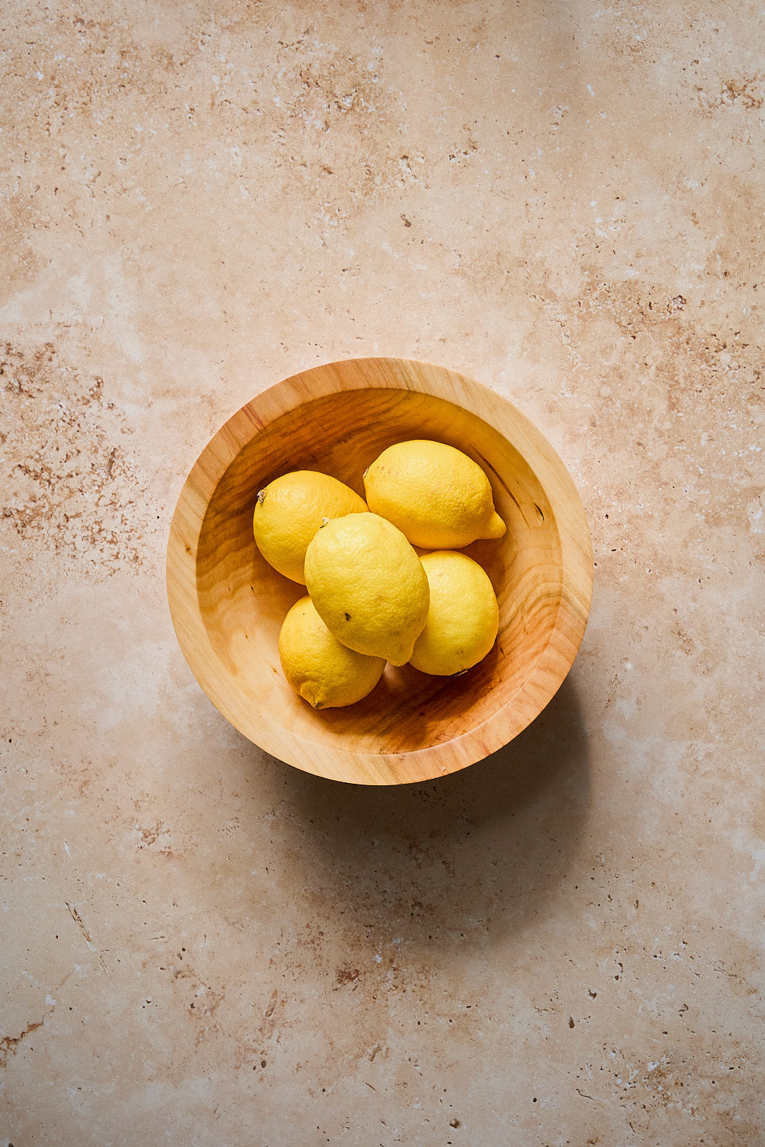Flat-lay showing the handmade wooden bowl full of lemons to show scale.