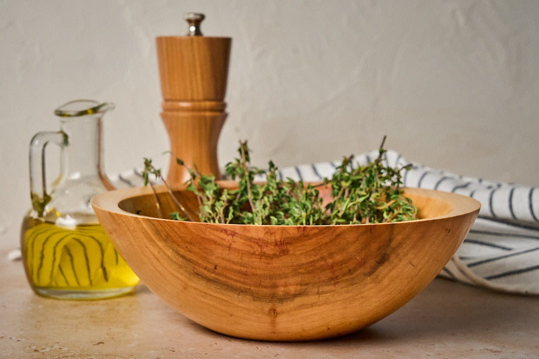 A side angle of the handmade wooden bowl filled with fresh herbs