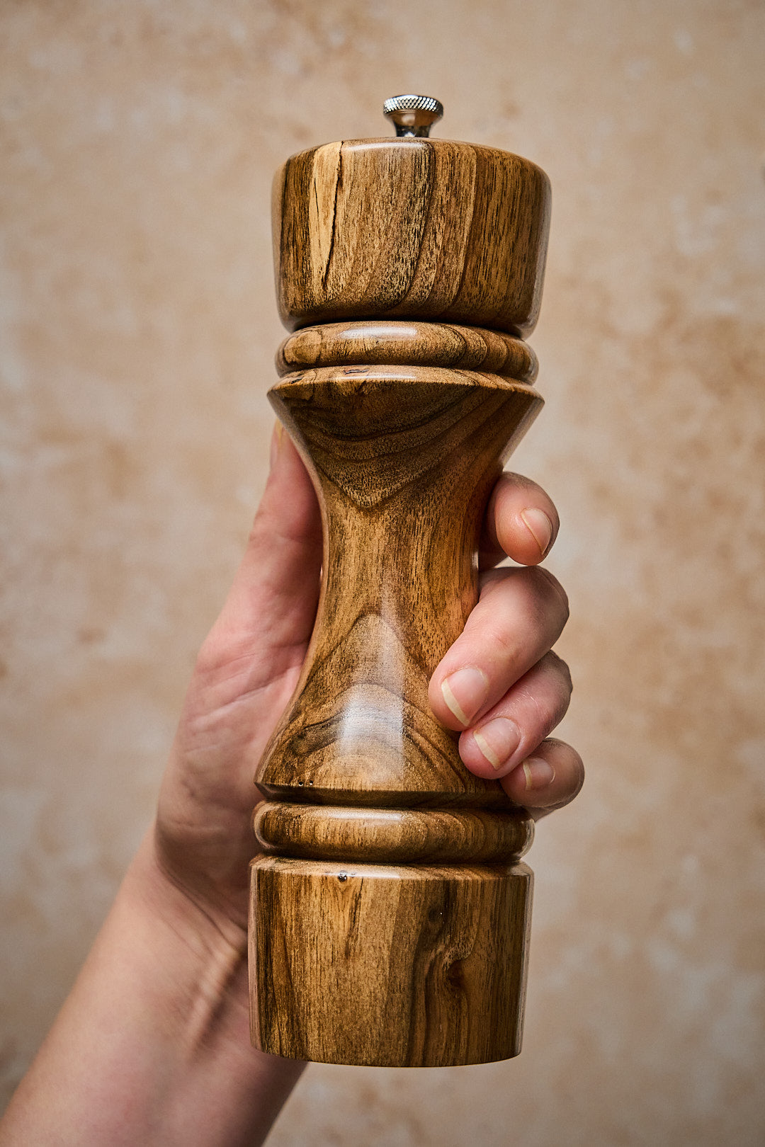 Hand holding big pepper grinder made from salvaged walnut