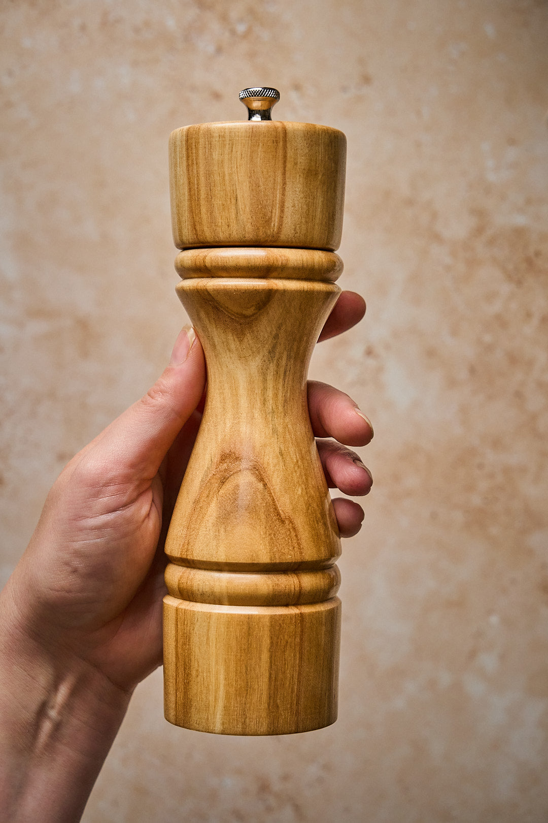 Hand holding the large handmade pepper mill.