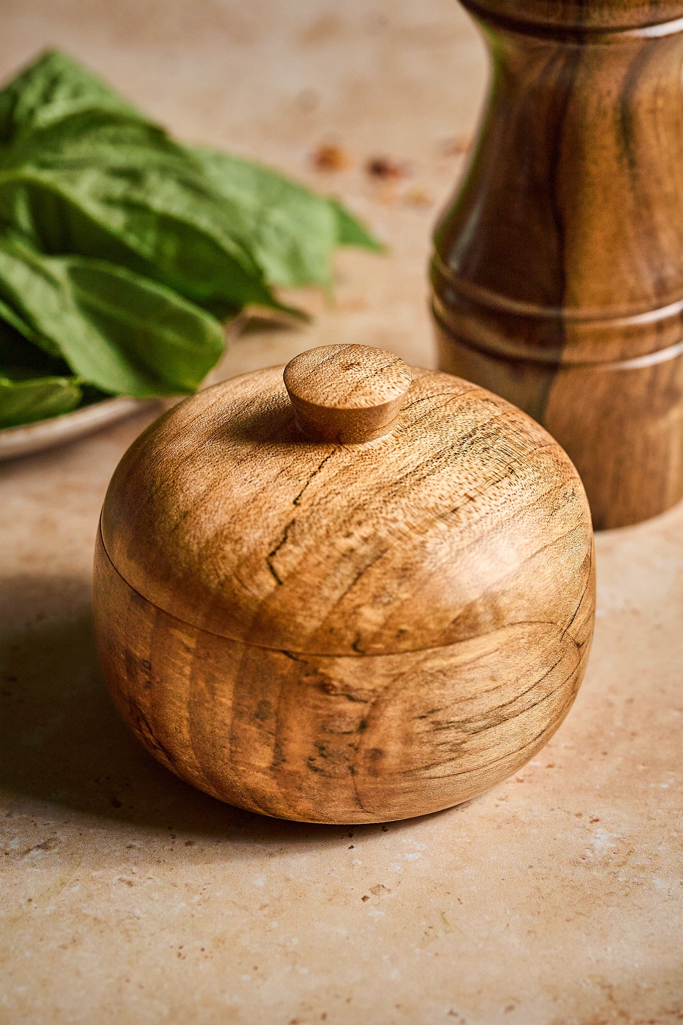 The wood salt cellar with the top on, showing the elegant rounded form
