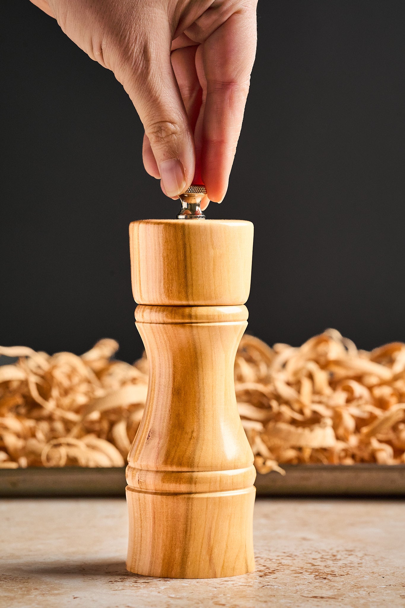 A hand reaching in to adjust the grinding mechanism on the modern pepper mill