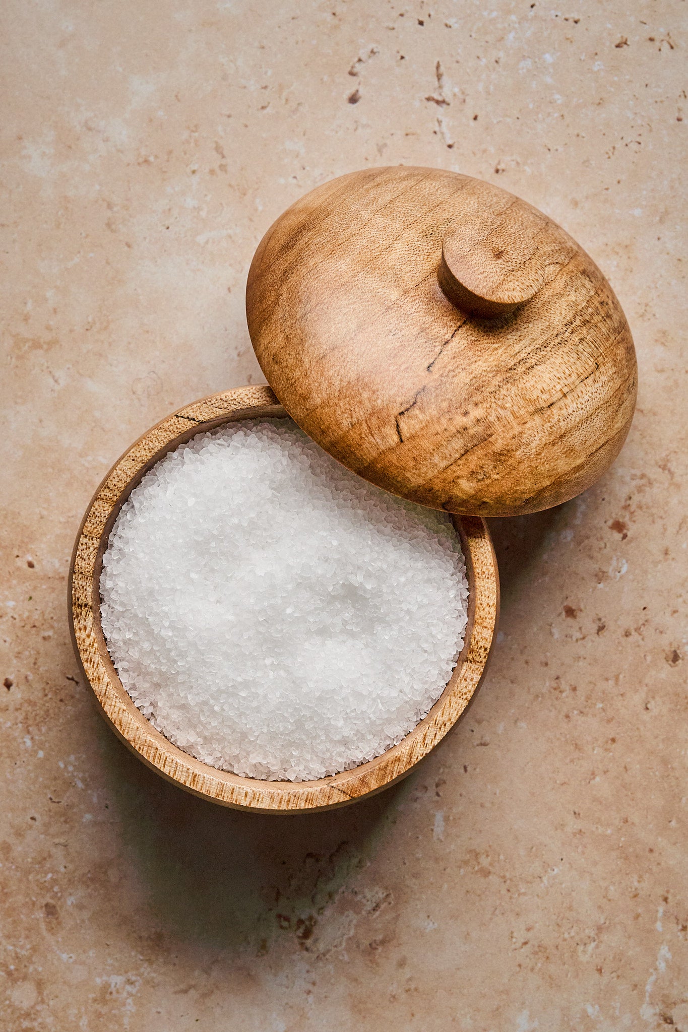 The lid is off of the wood salt cellar showing the salt inside