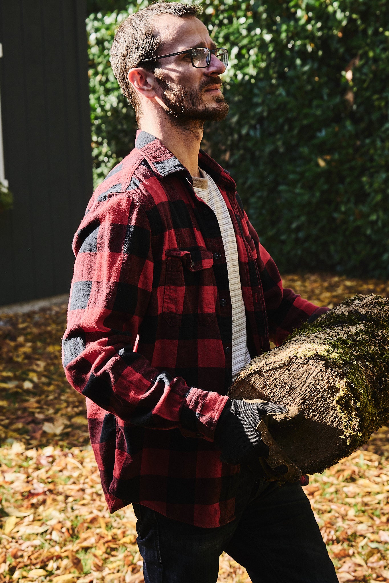 The artisan carries a log to his workshop where he makes handmade wood objects.