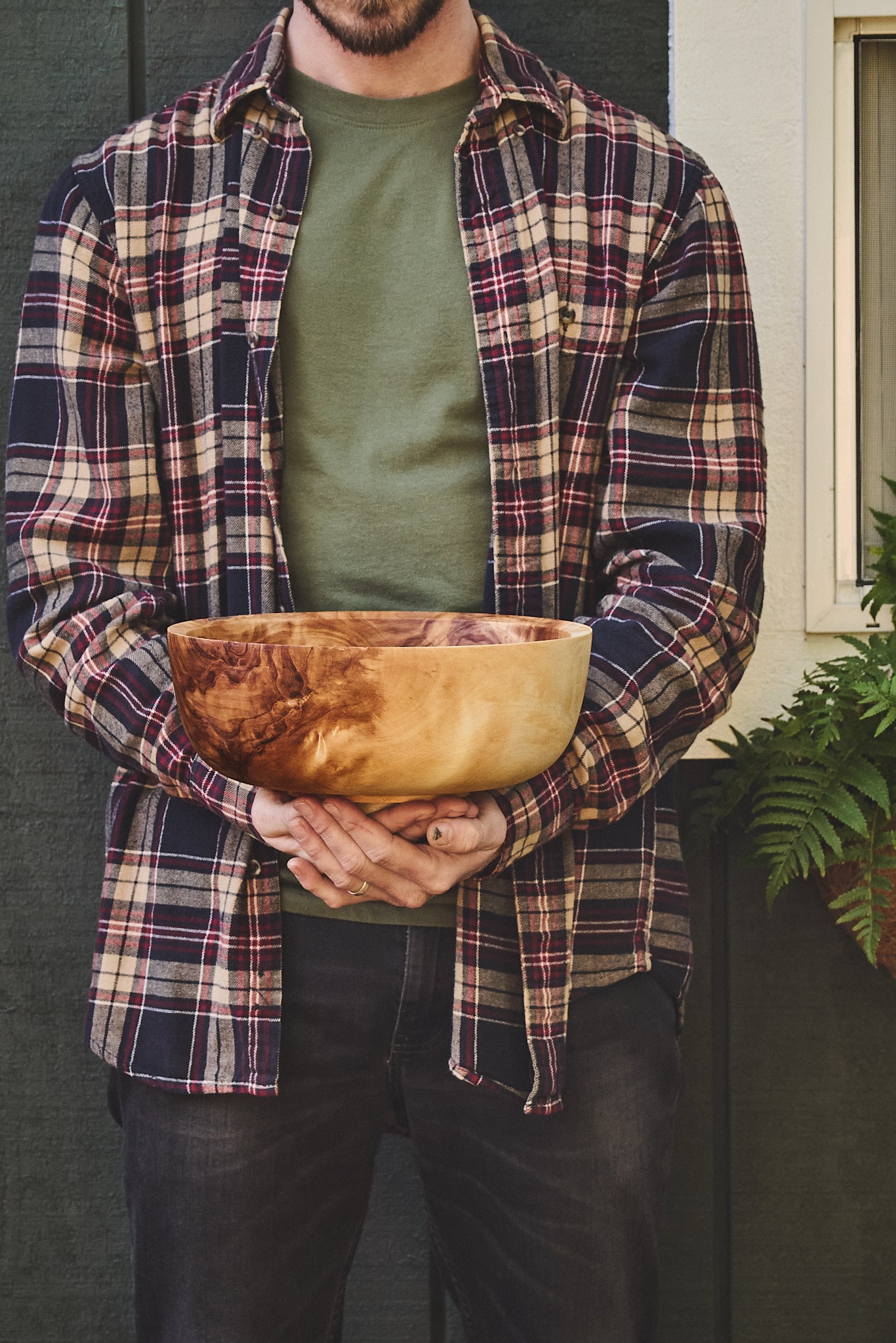 The artist holding the big wood salad bowl outside his green workshop in Oregon.