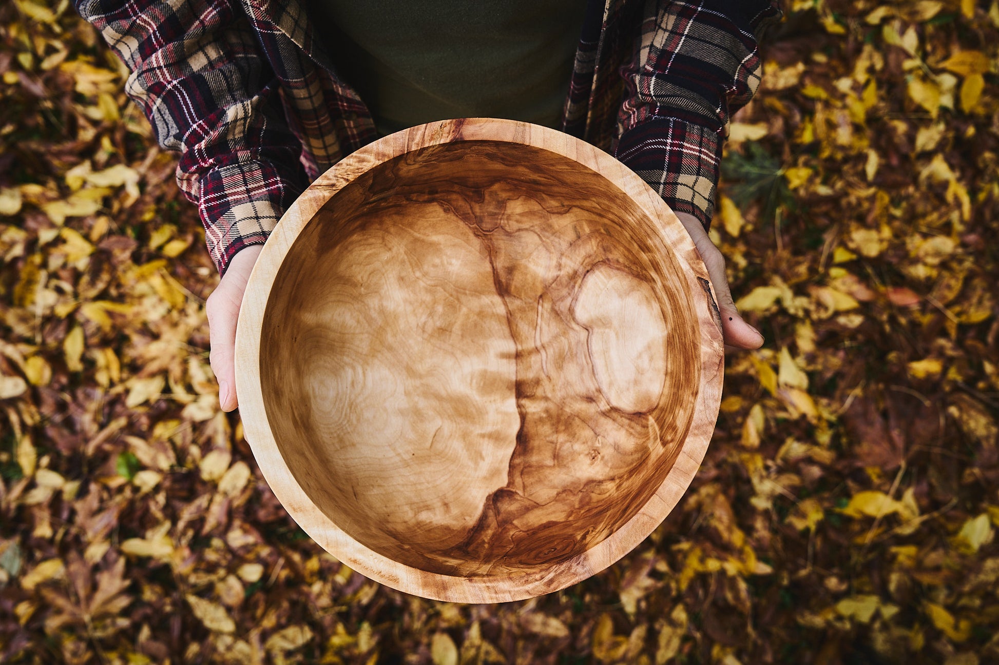 Big wood salad bowl crafted from salvaged Birch, held by the maker amidst fallen leaves.