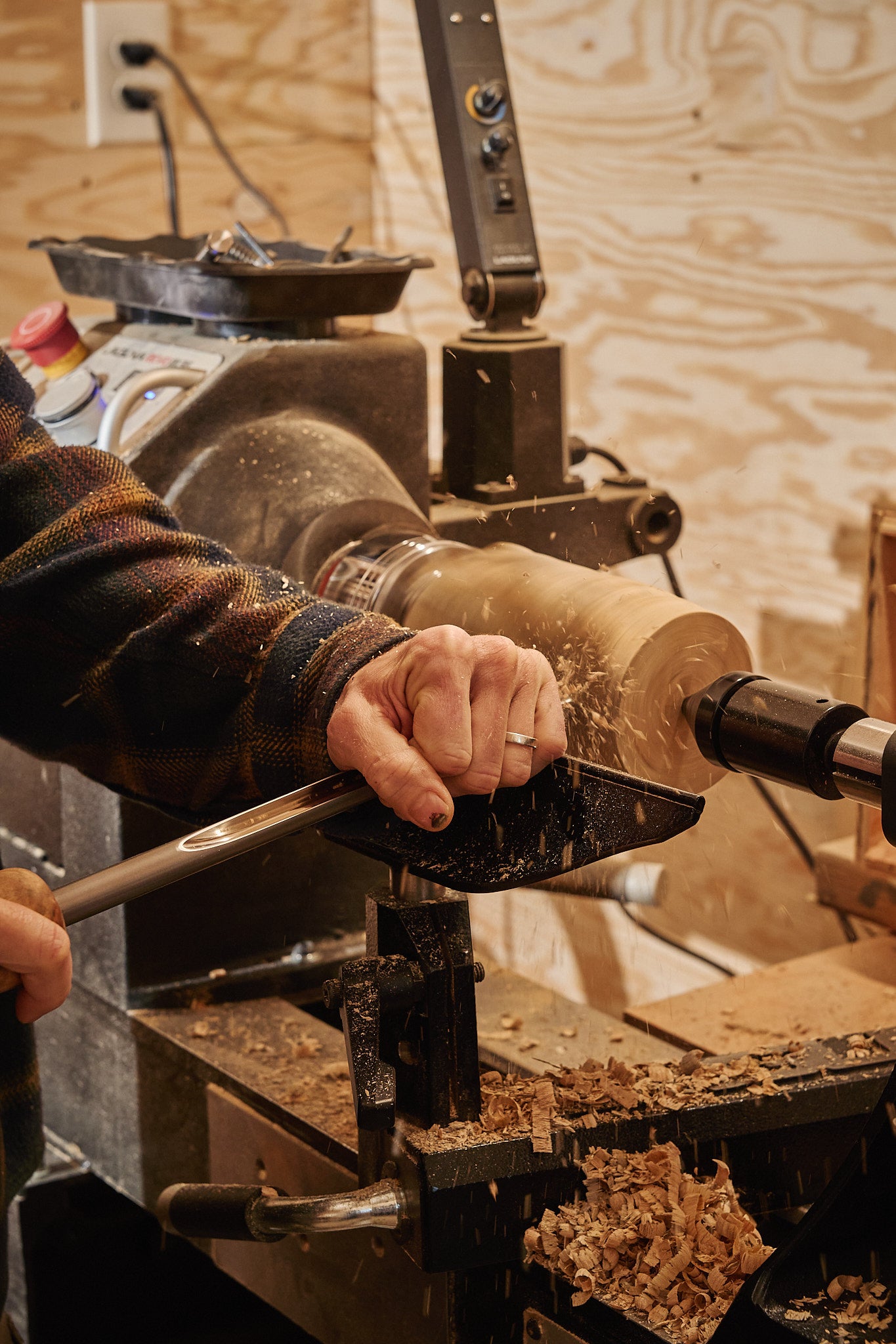 Craftsman using a lathe to create a handmade pepper grinder from birch wood.