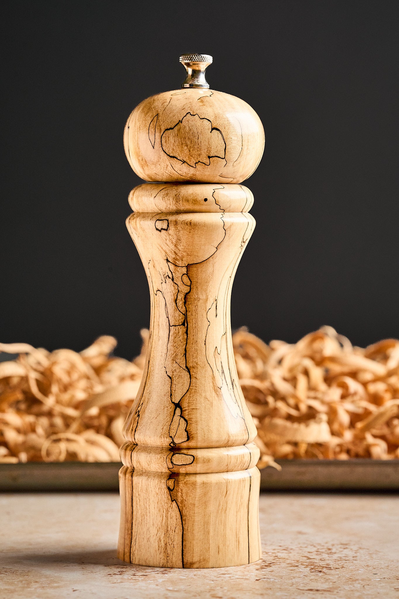 Side view of the tall pepper mill against a black background