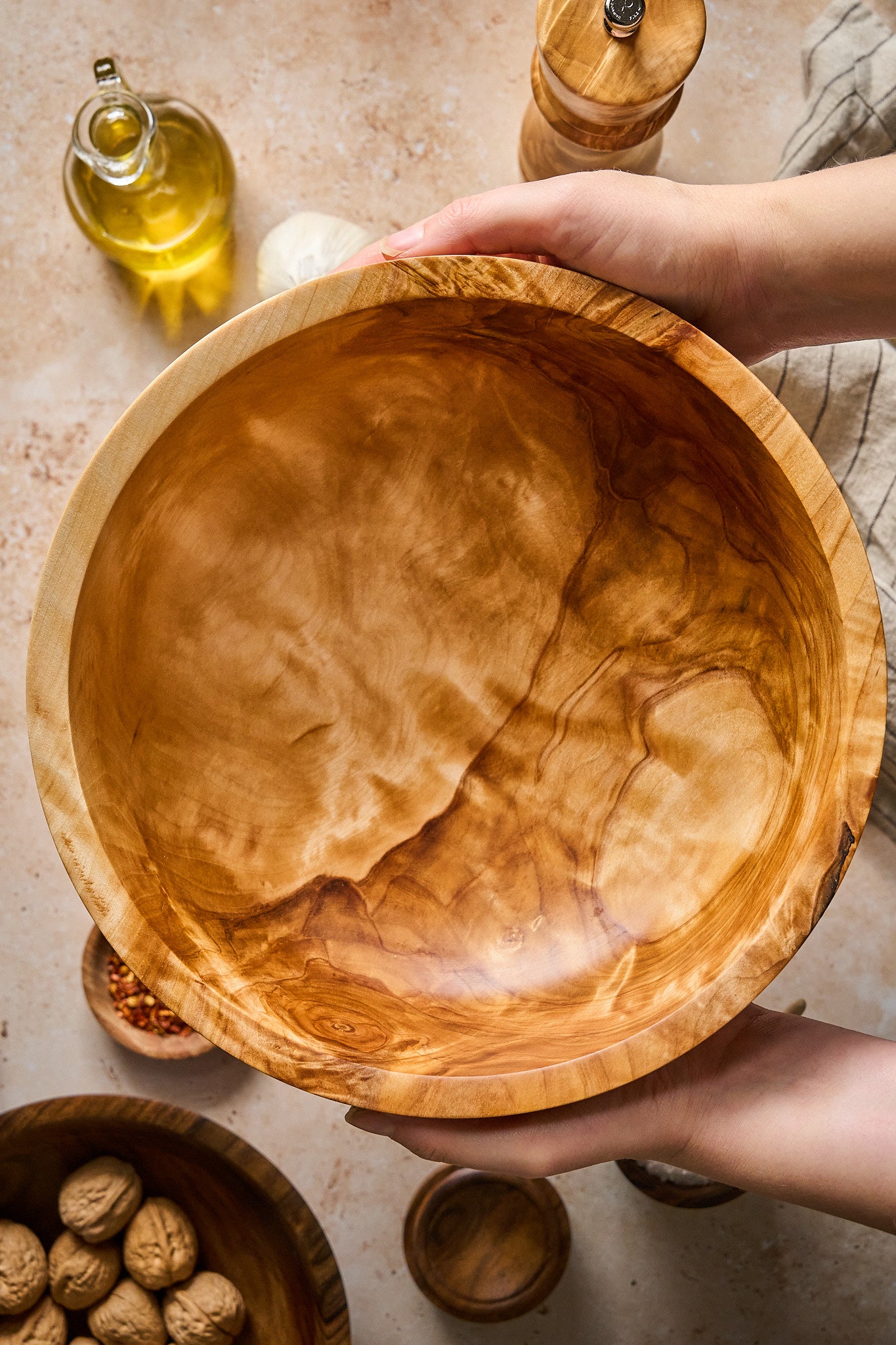 Big wood salad bowl held by hands, showcasing its handcrafted design and natural wood grain.